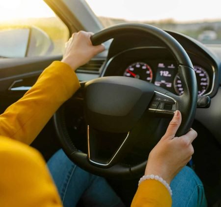 close-up-female-hands-in-yellow-suit-driving-car-o-2022-04-13-21-12-05-utc.jpg